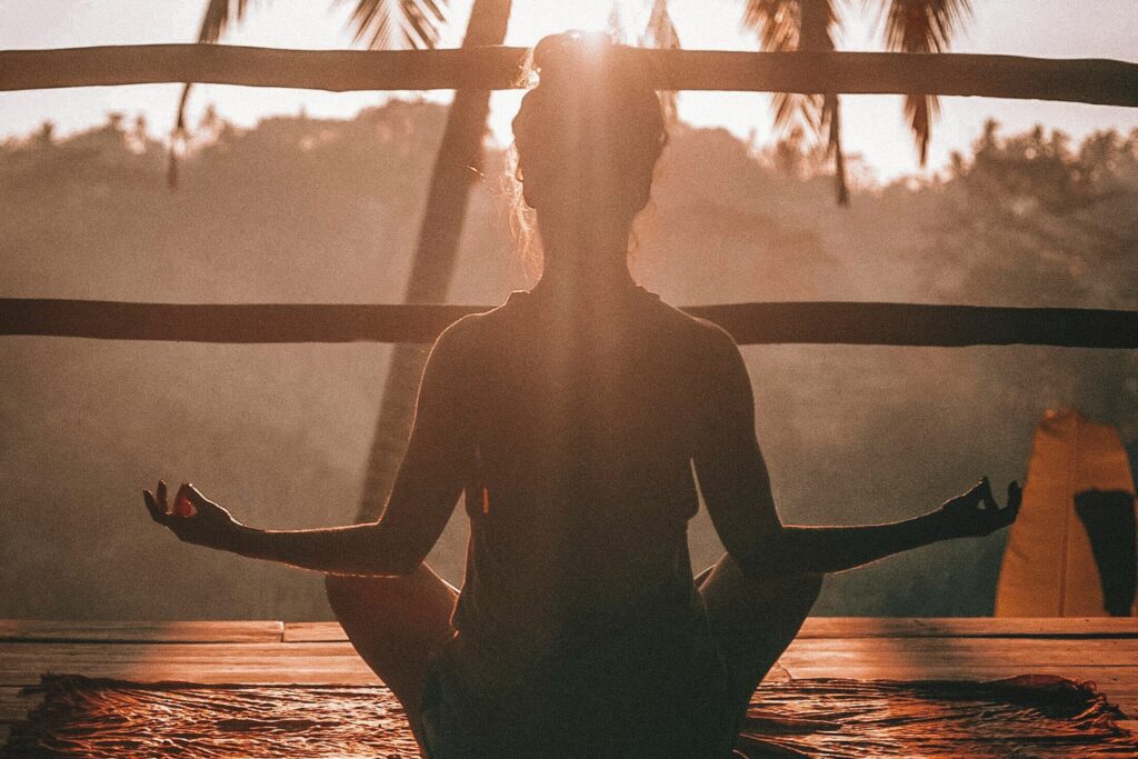 Kvinde i yogastilling ved solnedgang